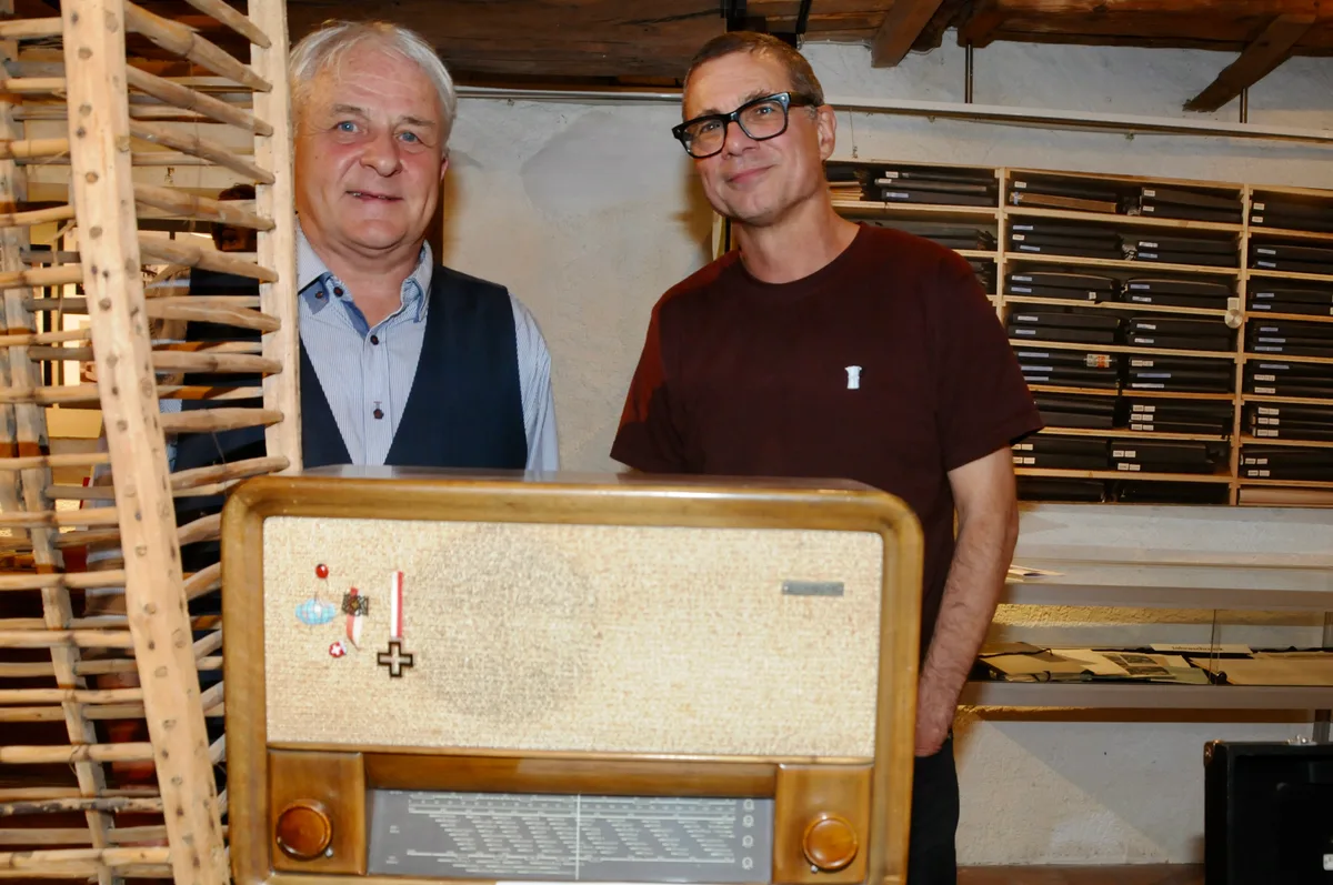 Mark Plüss (links) und Markus Brühlmeier mit Henri Feurers erstem Radio. Mark Plüss und Markus Brühlmeier stehen hinter einem alten Radio.